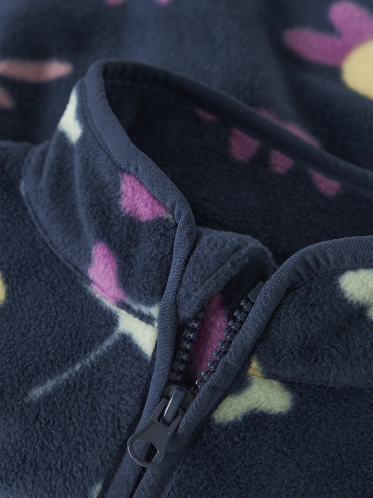 Close-up of a dark blue fleece jacket with pink and yellow floral patterns on a blurred background.