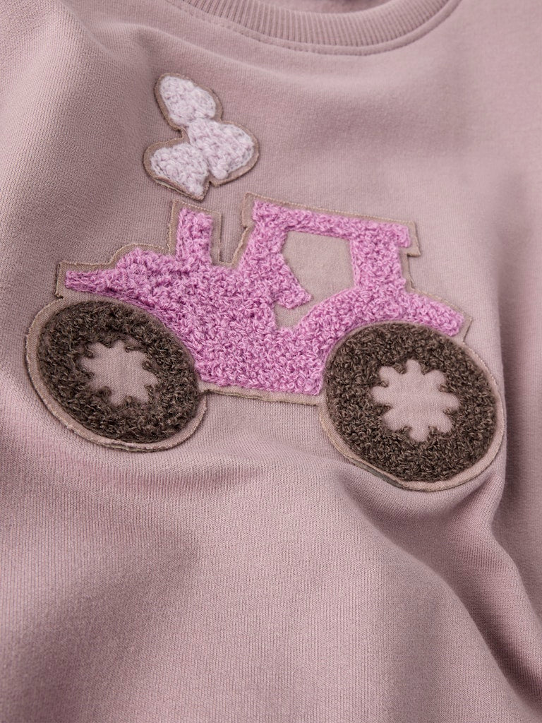 Close-up of a pink tractor patch on a light purple sweatshirt.