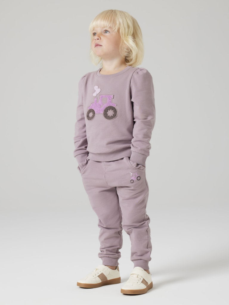 Child wearing a purple tracksuit with a design on a plain background