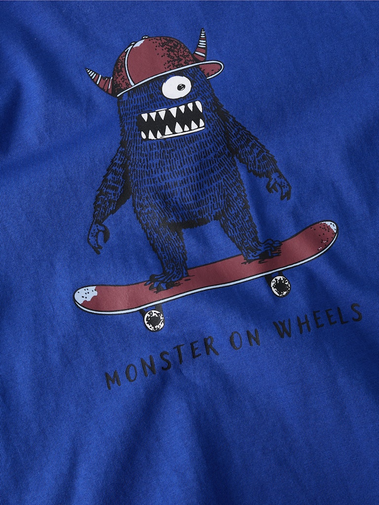 Blue t-shirt with a cartoon monster on wheels design on a blue background