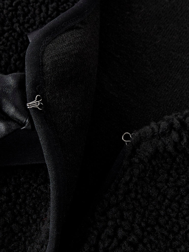 Close-up of a black suit jacket with a bow tie on a textured background