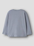 A light blue-gray long-sleeve t-shirt shown from the back, laid flat against a neutral light gray background.