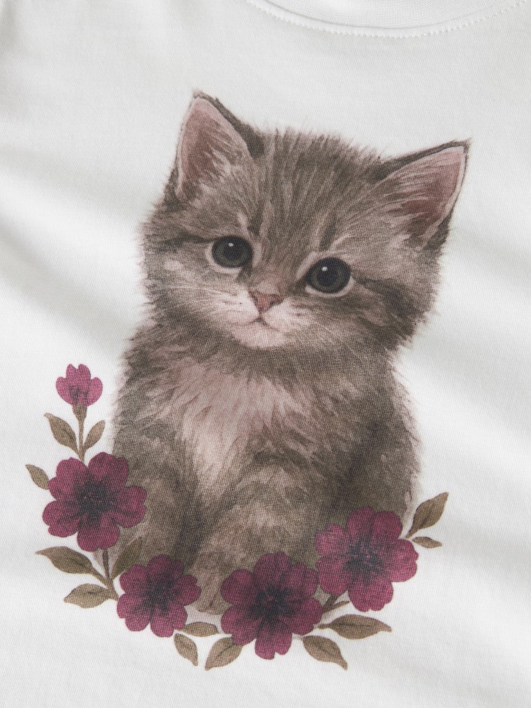 A close-up of a white garment featuring a printed illustration of a fluffy gray kitten surrounded by dark pink flowers and green leaves.