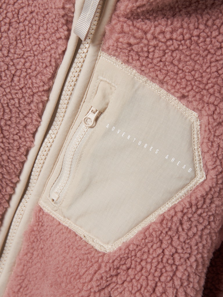 Close-up of a pink fleece jacket with a pocket and zipper.