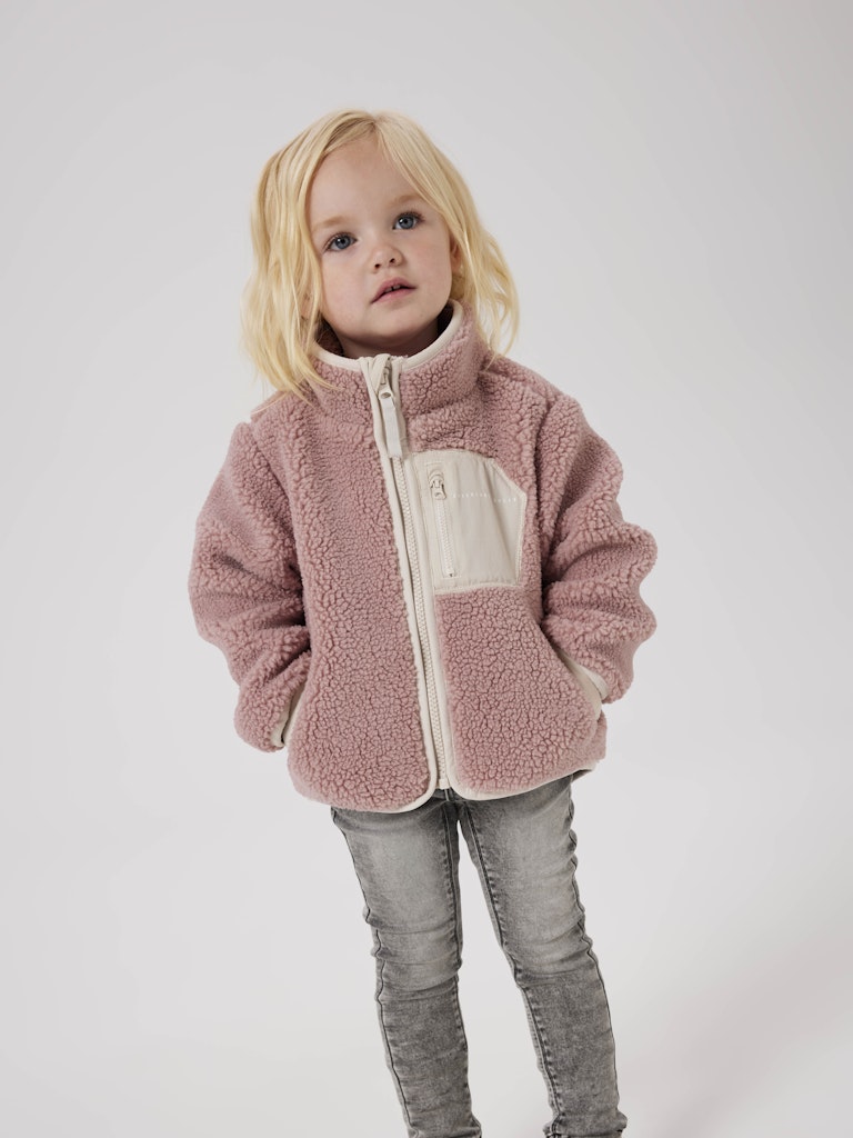 Child wearing a pink fleece jacket on a white background