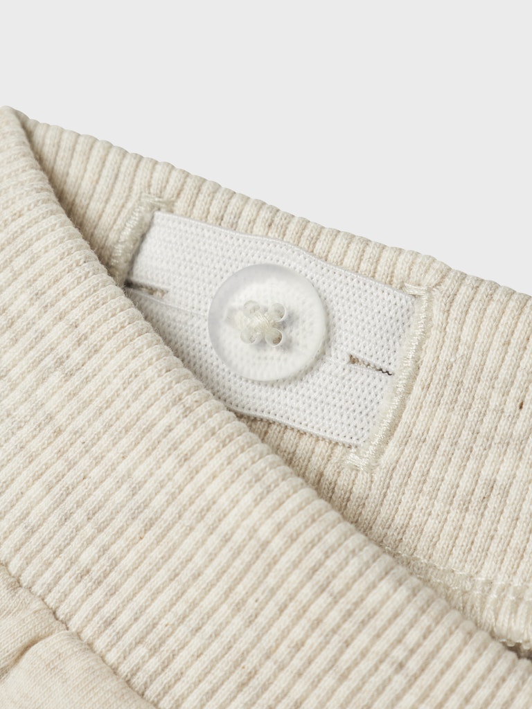 Close-up of a textured beige fabric with a button adjuster on a white background