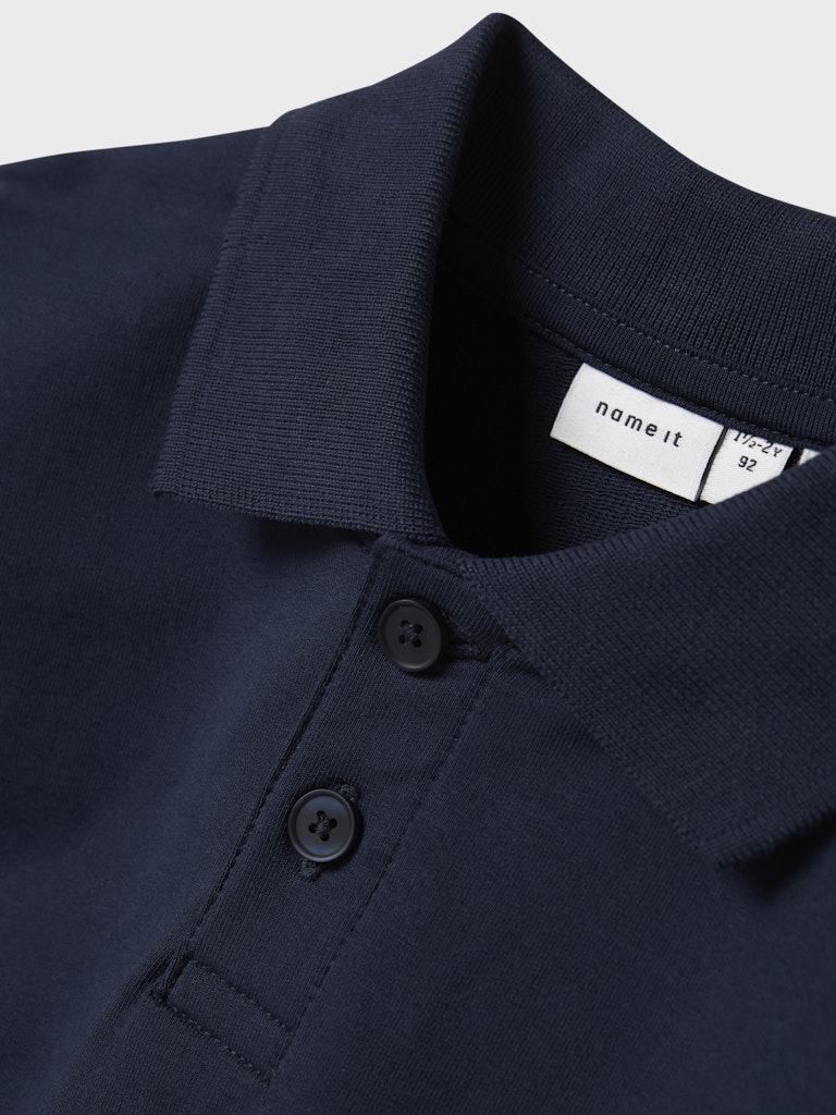 Navy blue polo shirt with brand label on collar against a light gray background