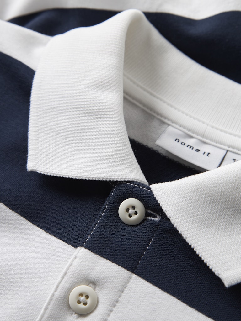 Close-up of a white and navy striped polo shirt with a brand label.