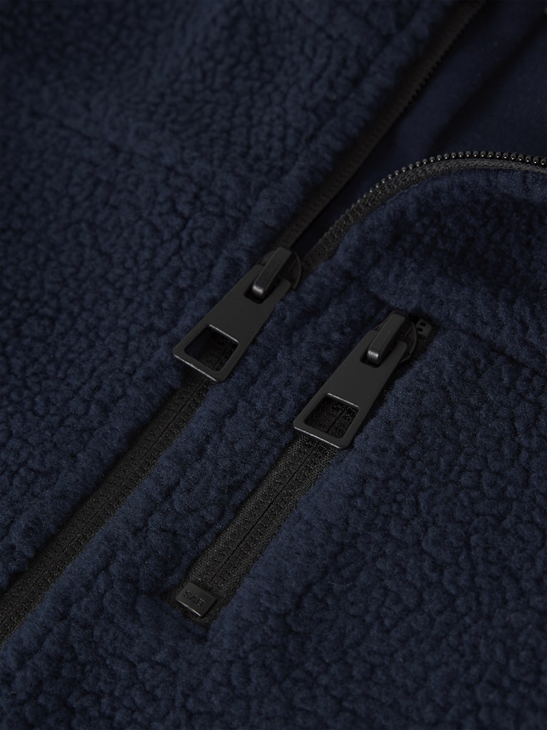 Close-up of a black zipper on a textured navy fabric background