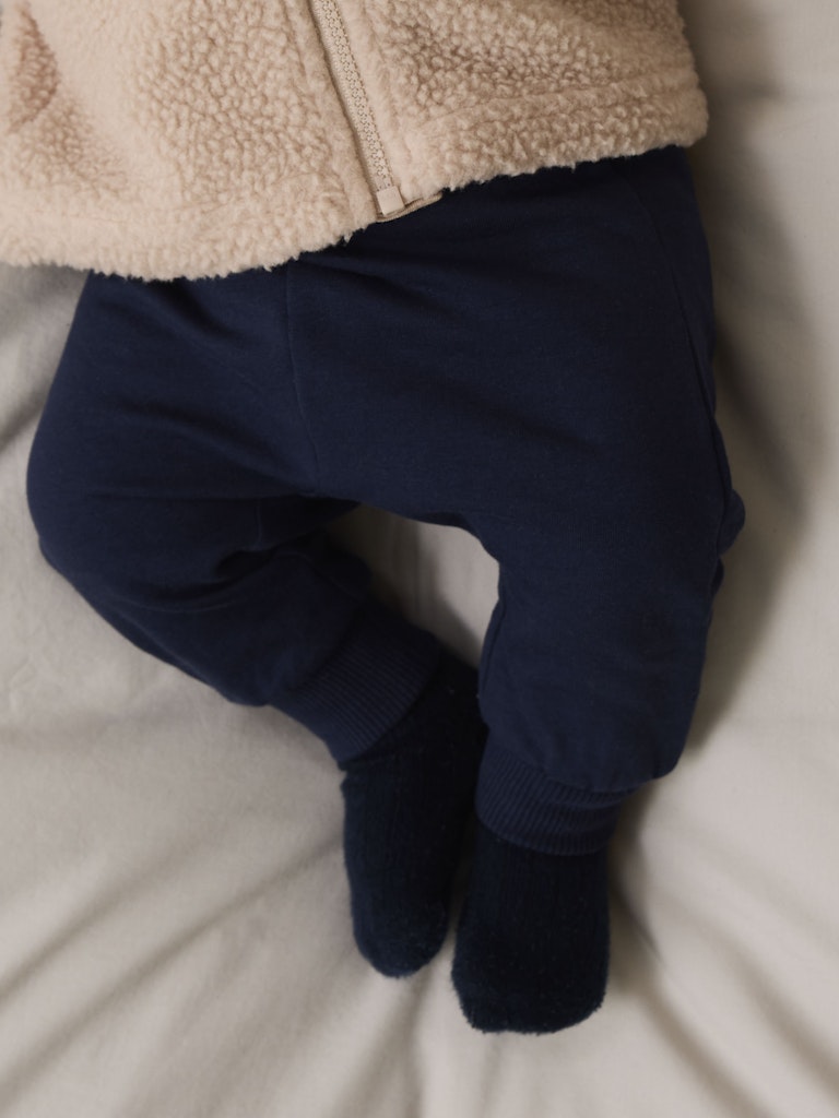 Navy blue pants and beige fleece jacket on a light background
