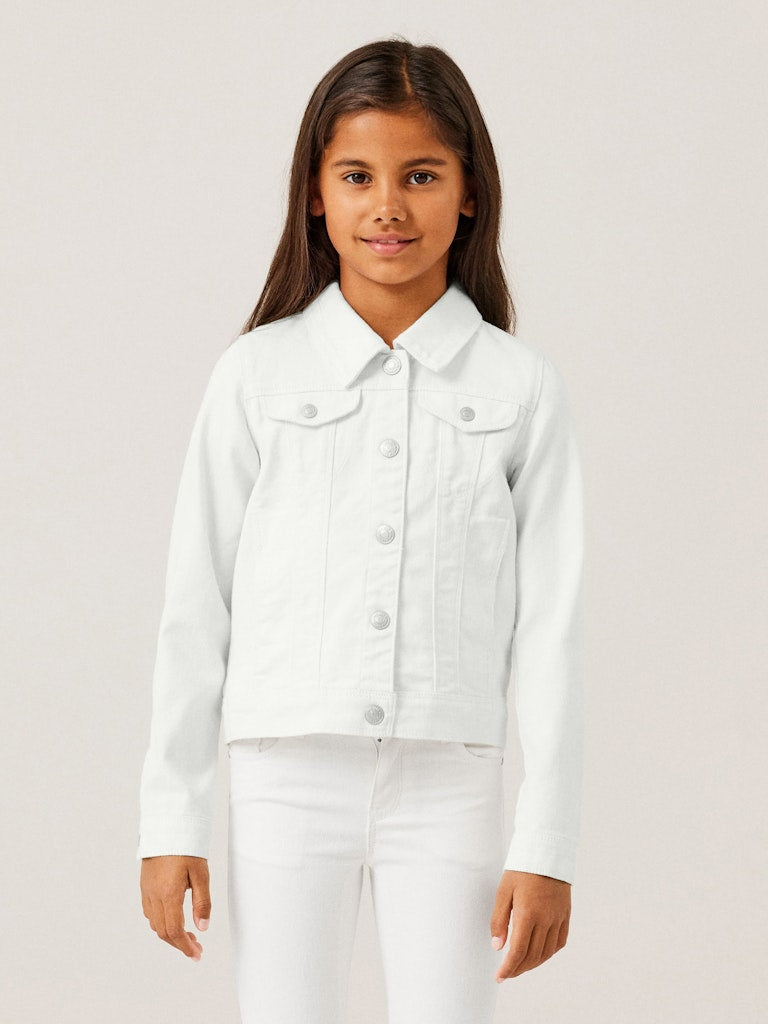 Young girl wearing a white denim jacket and pants on a plain background