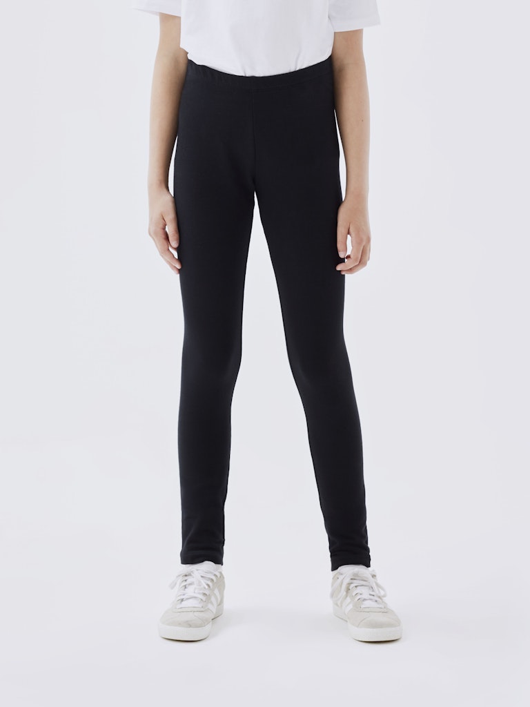 Person wearing black leggings and white sneakers on a white background