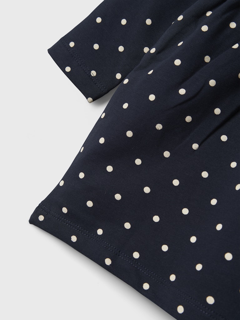 Navy blue fabric with white polka dots on a light gray background