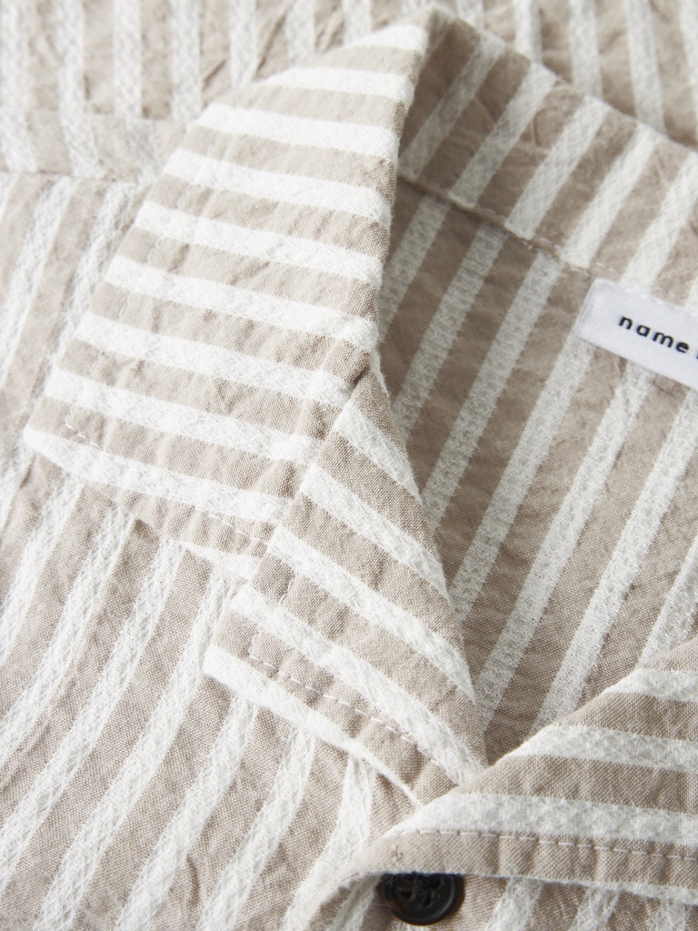 Close-up of a beige and white striped fabric with a brand label.