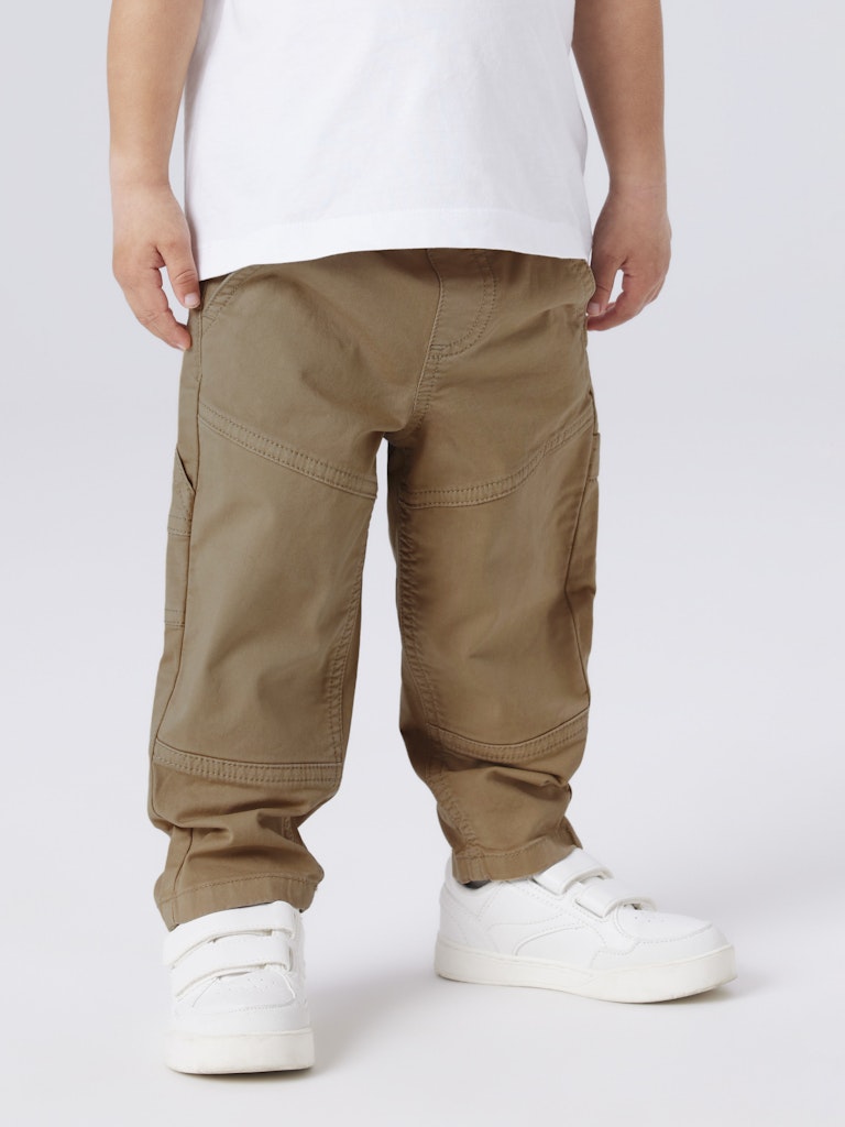Person wearing brown cargo pants and white sneakers on a plain background