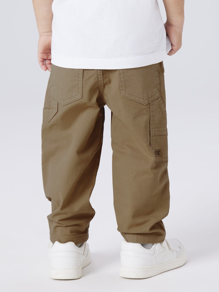 Person wearing brown cargo pants and white sneakers on a white background