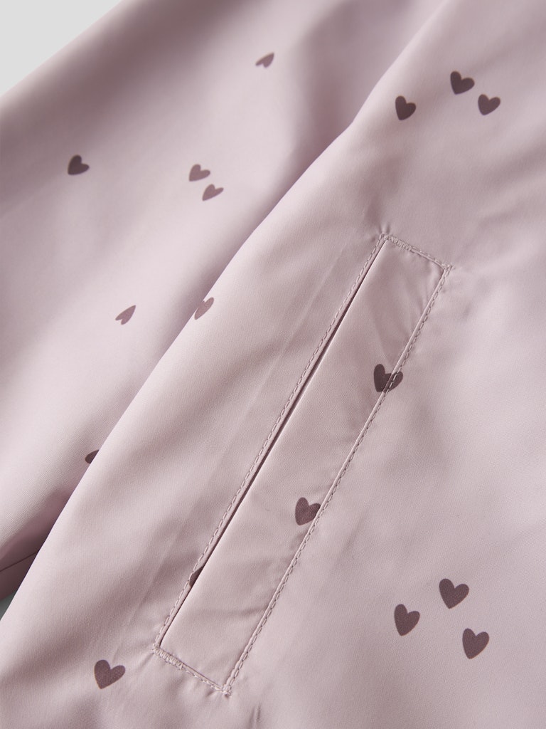 Close-up of a pink fabric with heart patterns and stitching details.