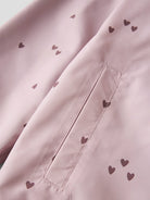Close-up of a pink fabric with heart patterns and stitching details.