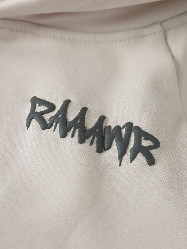 Beige hoodie with green 'RAAWR' text on a close-up of the fabric.