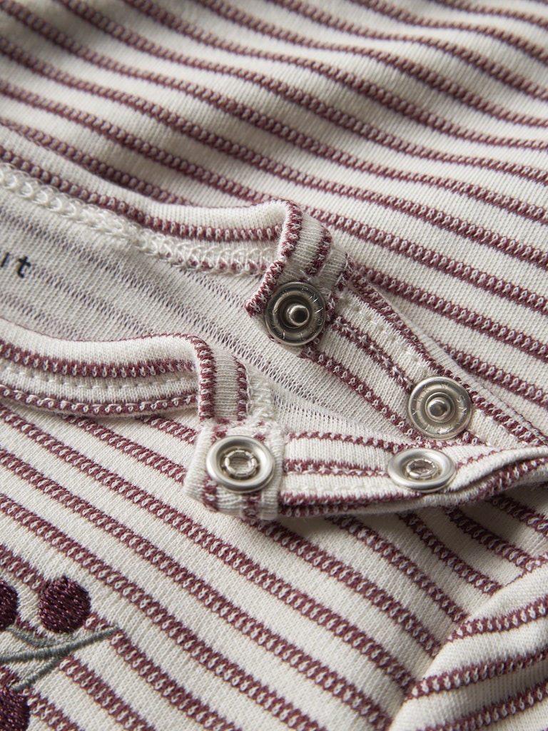 Close-up of a striped fabric with buttons and a small floral design.