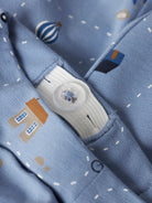 Close-up of a blue fabric with cartoon designs and a button, featuring small balloons and houses.