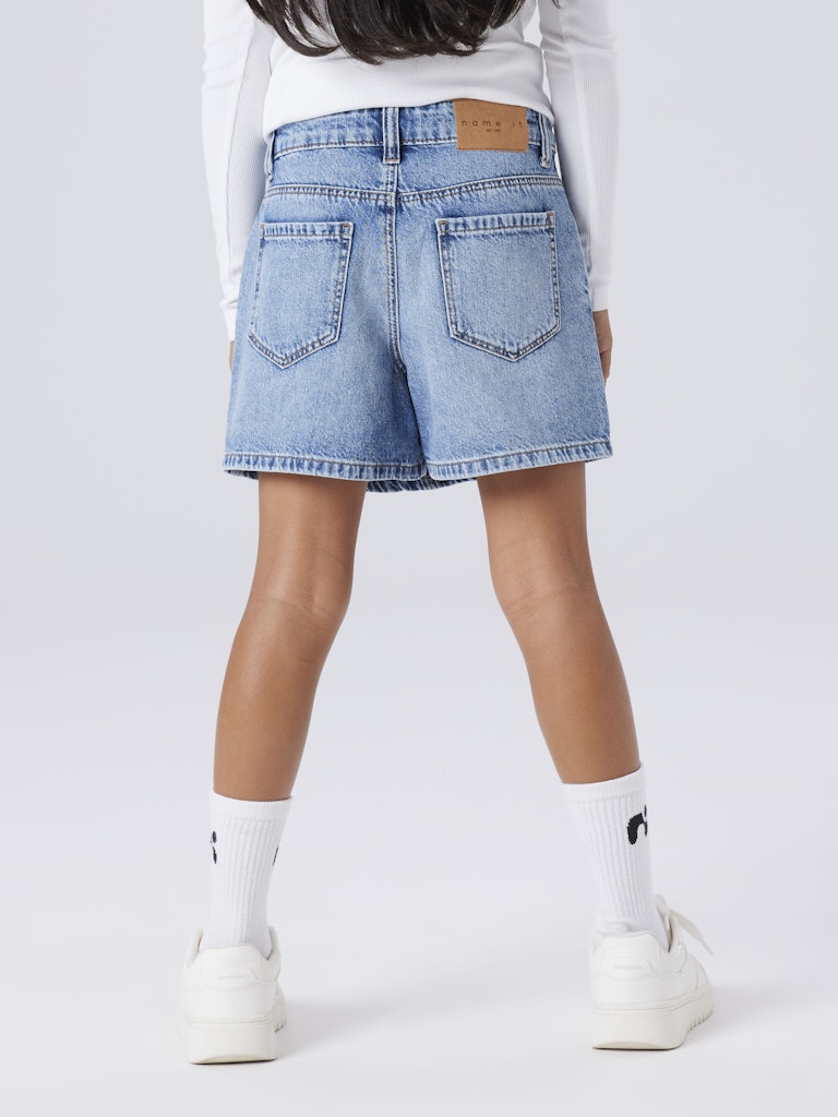 Person wearing light blue denim skort on a white background