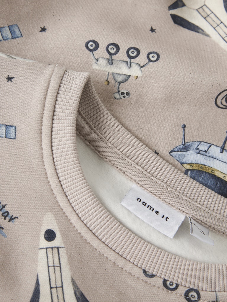 Close-up of a fabric with space-themed design and 'name it' label.