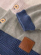 Close-up of a knitted garment with buttons and a brand label.