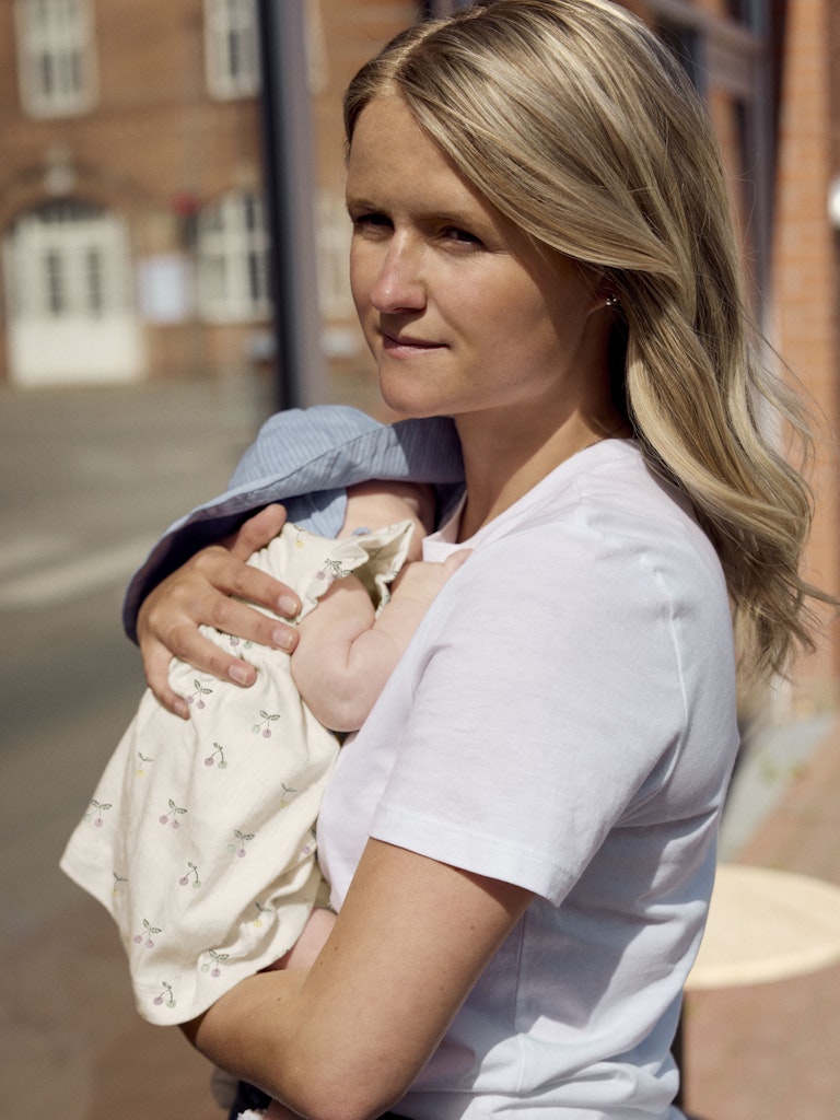 Woman holding a baby outdoors with a building in the background