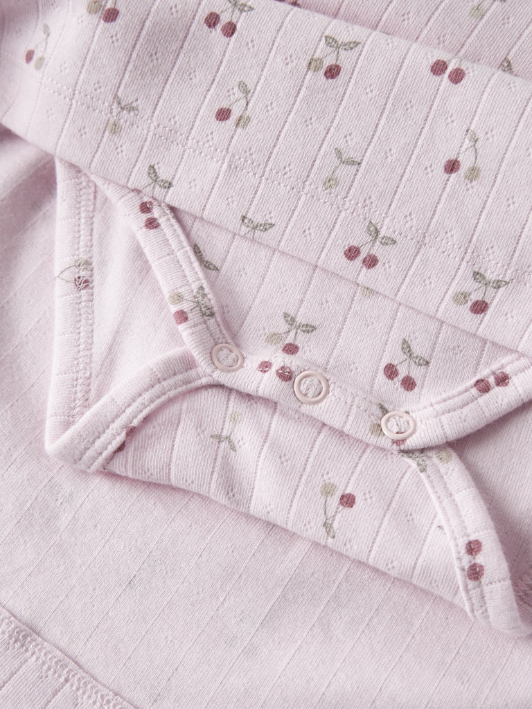 Folded pink dress with floral embroidery on a matching fabric background