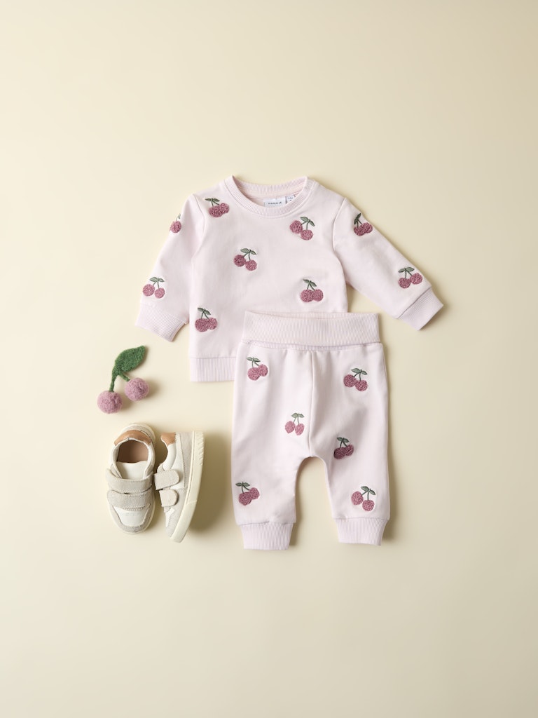 Baby outfit with cherry pattern on a light beige background