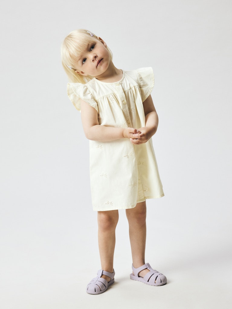 Young girl wearing a light-colored dress on a plain background