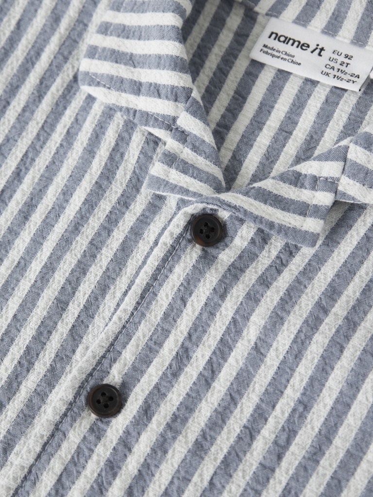 Close-up of a striped shirt with a brand label on a white background