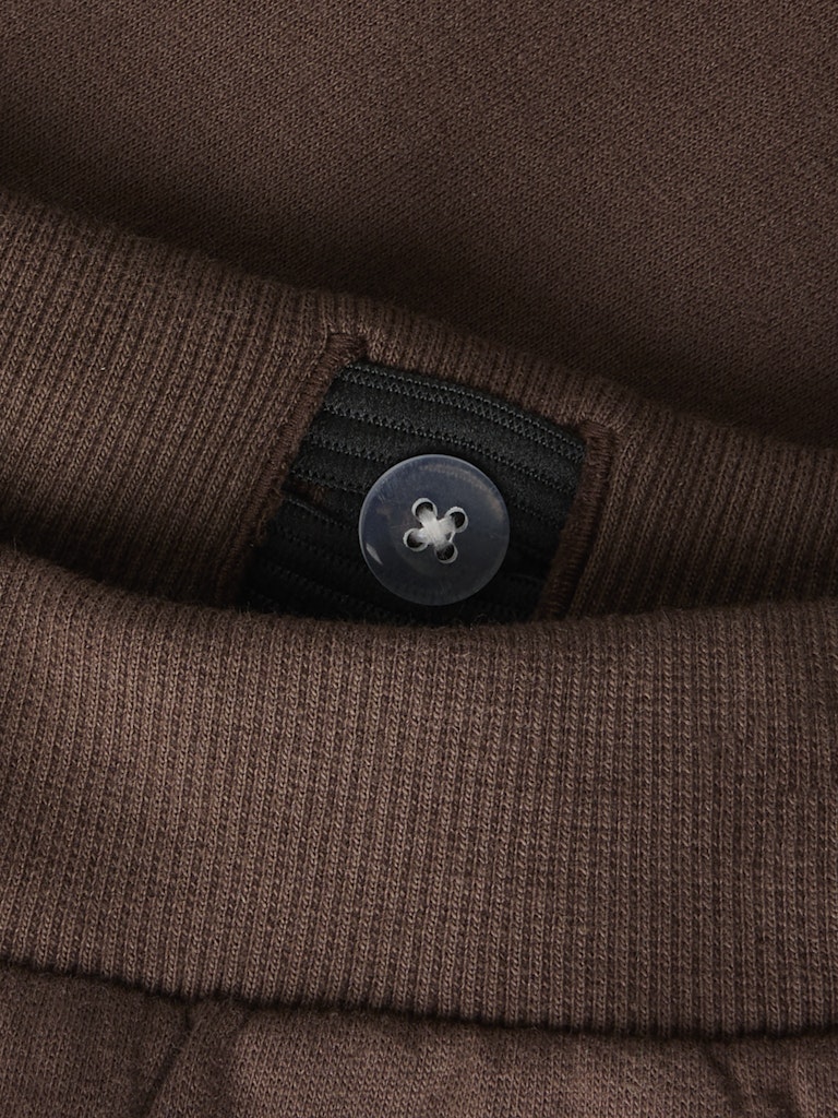 Close-up of brown sweatpants with a button adjustable waist.