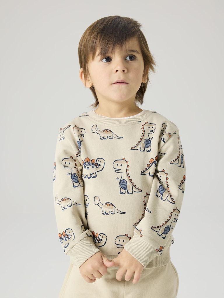 Child wearing a sweater with dinosaur patterns on a plain background