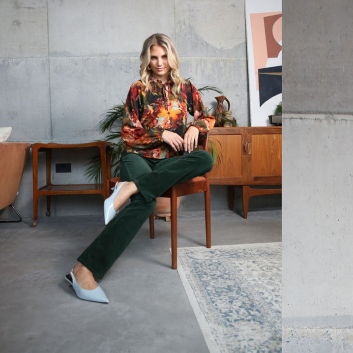 Woman sitting on a chair in a modern room with wooden furniture and a concrete wall.