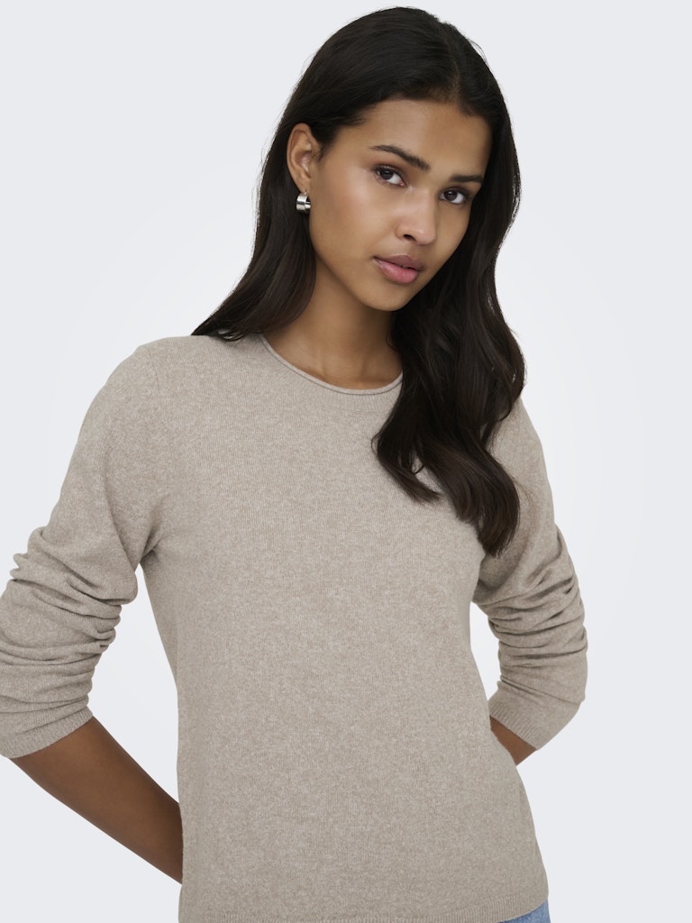 Woman wearing a beige sweater on a plain background