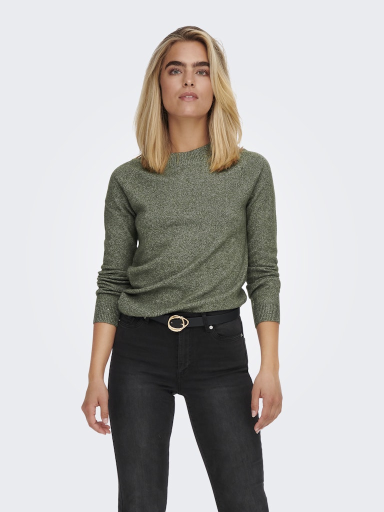 Woman wearing a green sweater and black jeans on a white background