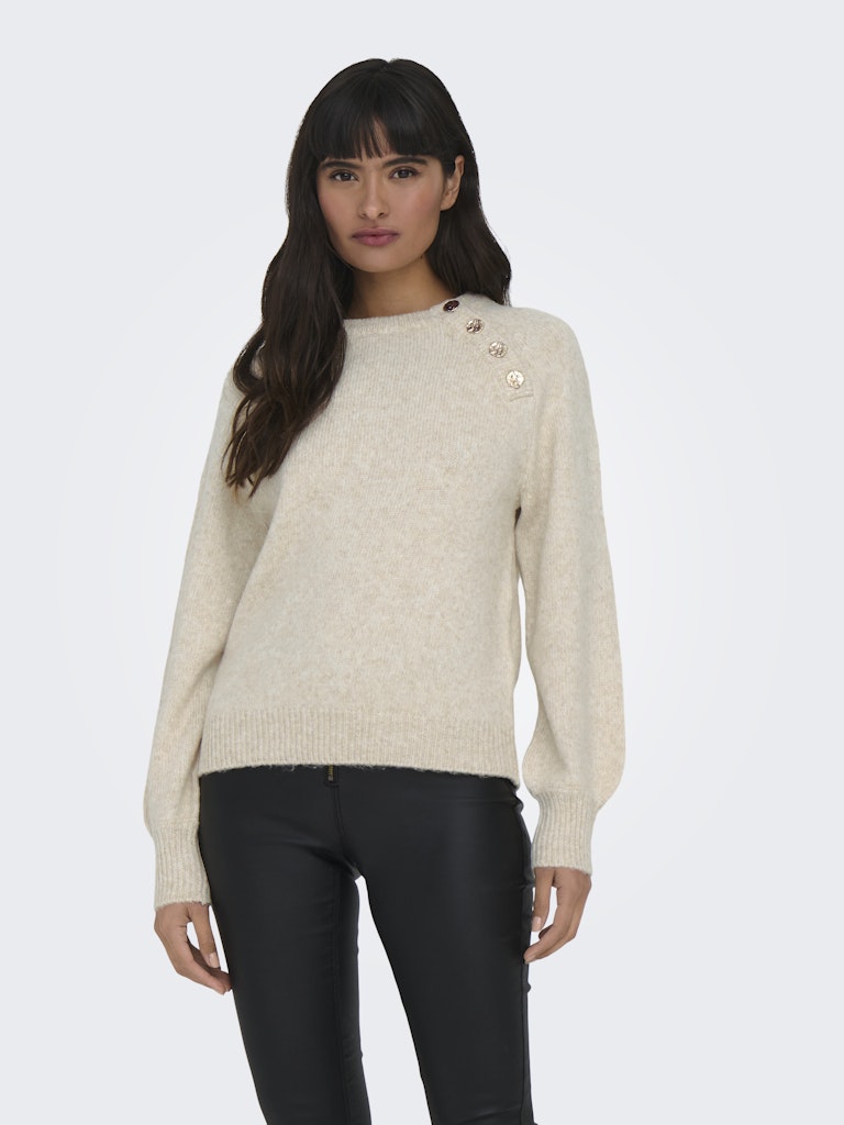 Woman wearing a beige sweater with black pants on a white background