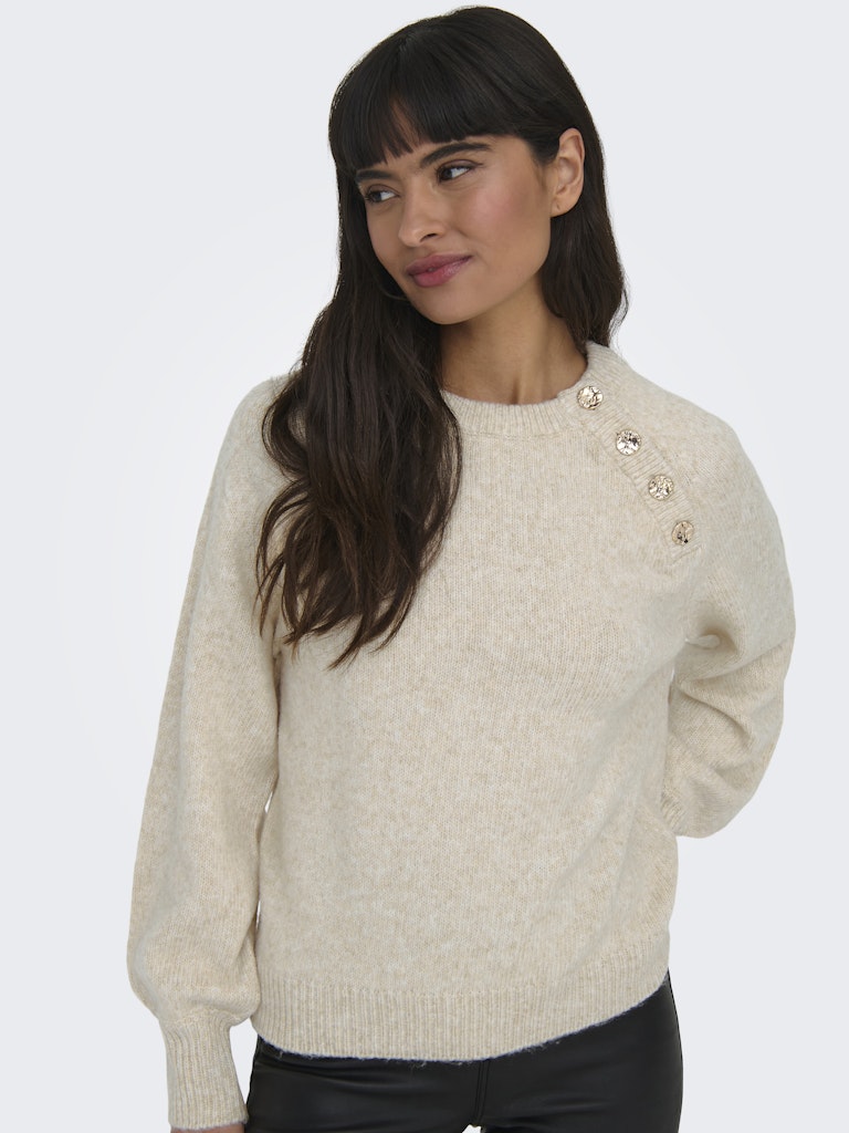 Woman wearing a beige sweater with button details on a white background
