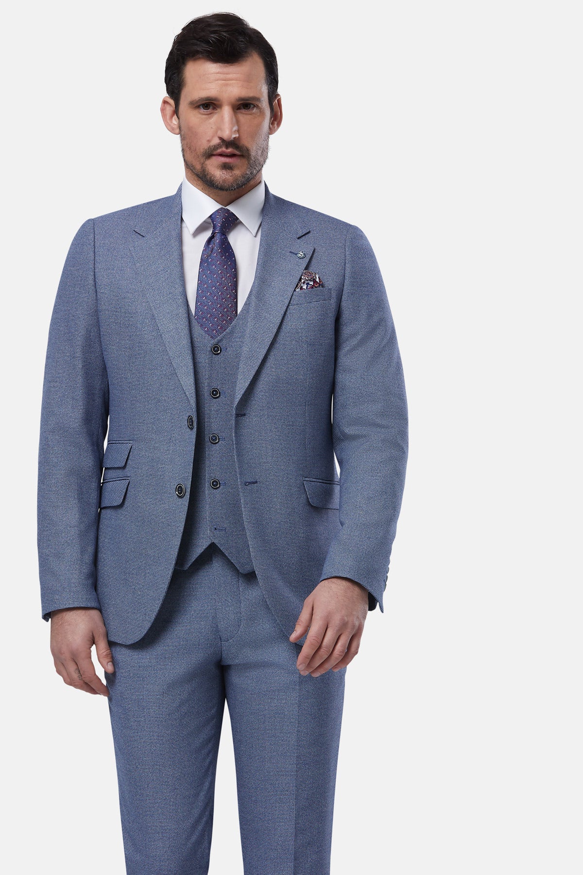 Man wearing a light blue suit with a white shirt and patterned tie on a white background
