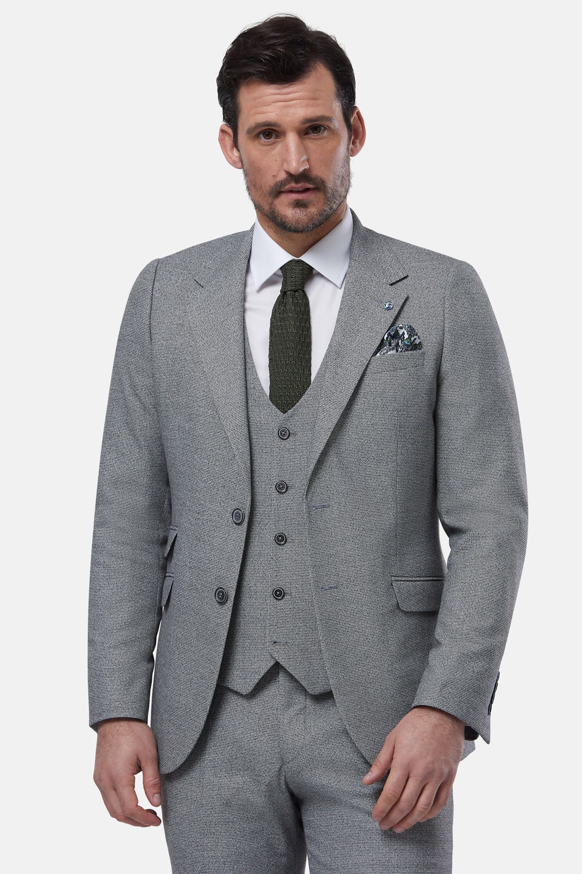 Man wearing a gray suit with a white shirt and green tie on a light gray background