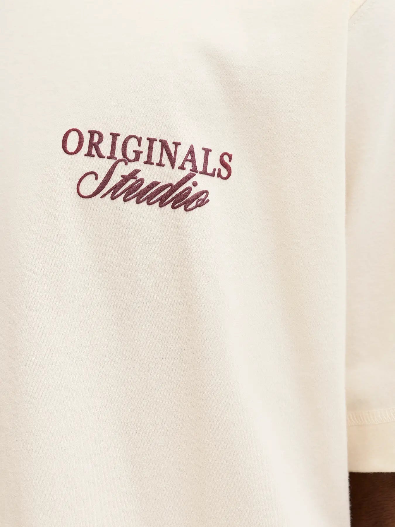 Beige sweatshirt with 'ORIGINALS Studio' text in maroon on a white background