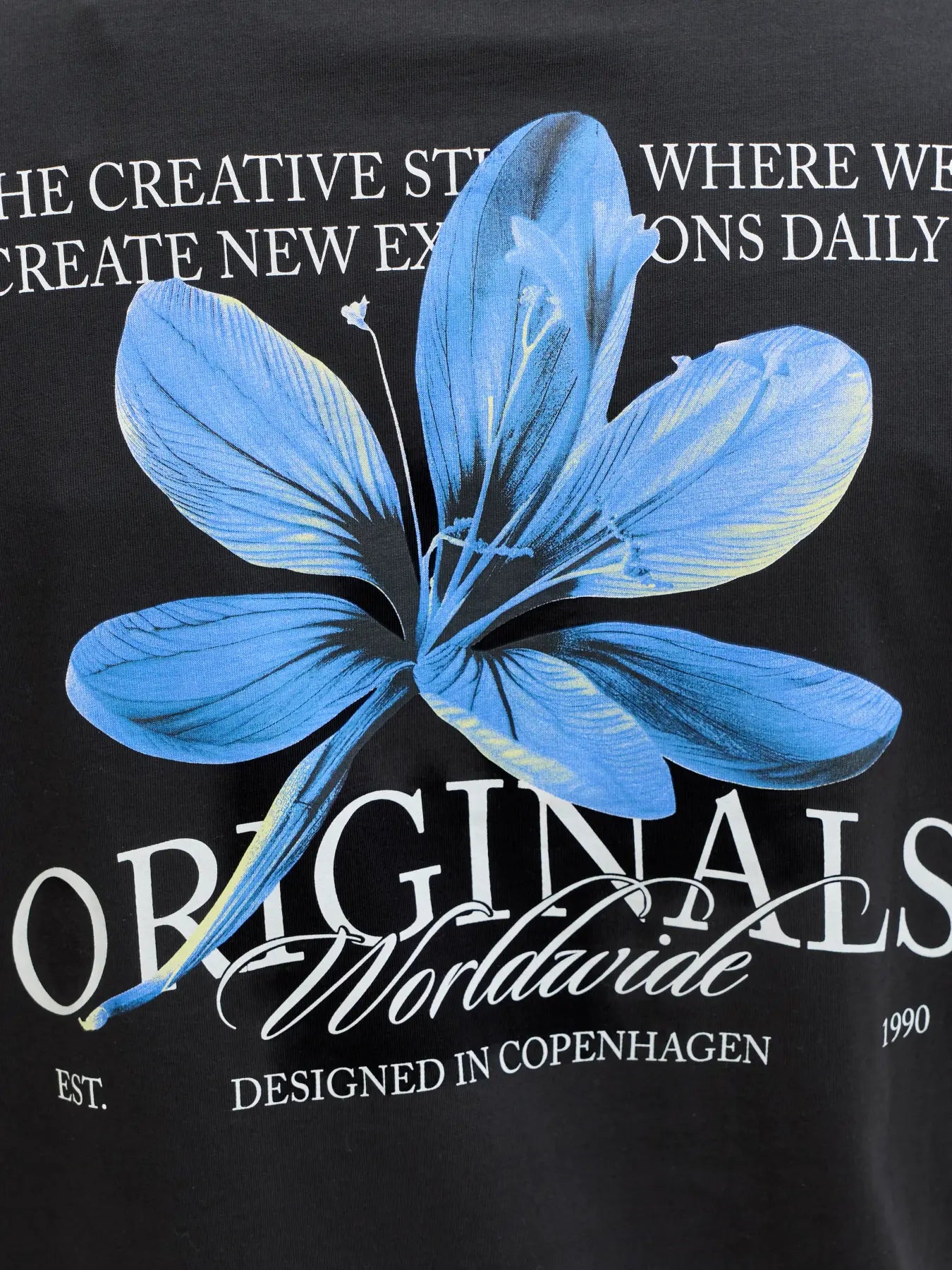 Black t-shirt with blue floral design and text on a black background