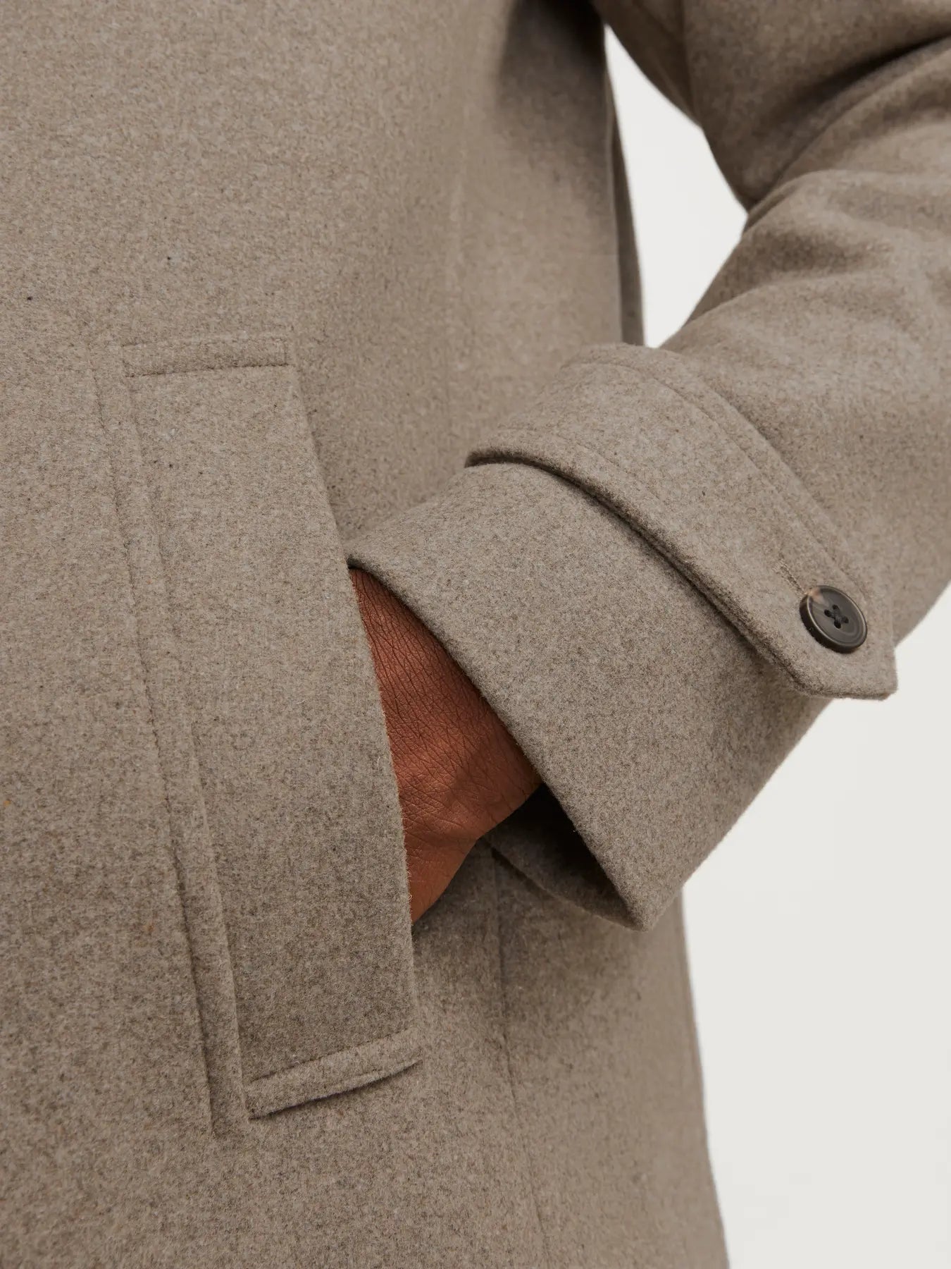 Close-up of a beige coat with a button on a light gray background