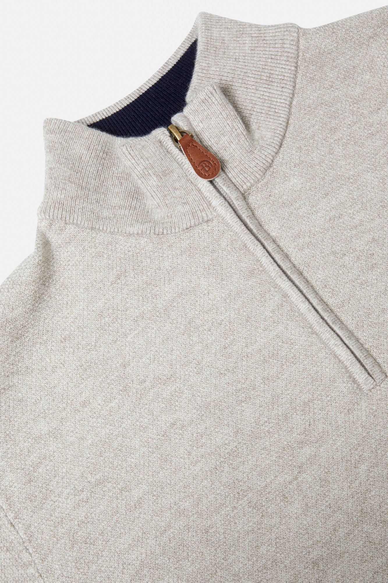 Close-up of a gray sweater with a zipper and leather pull tab.