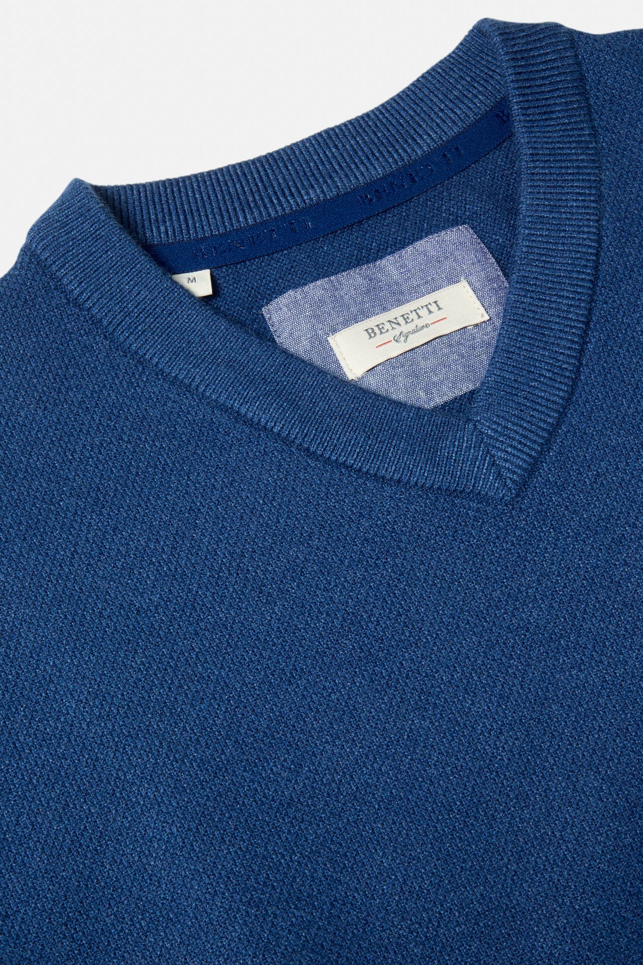 Close-up of a Benetti Quinn Indigo V Neck Knit showing the V-neck collar, ribbed trim, and interior label.