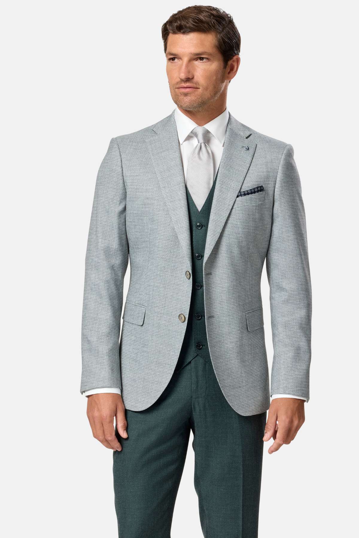 Man wearing a sage green suit with a white shirt and green vest on a white background