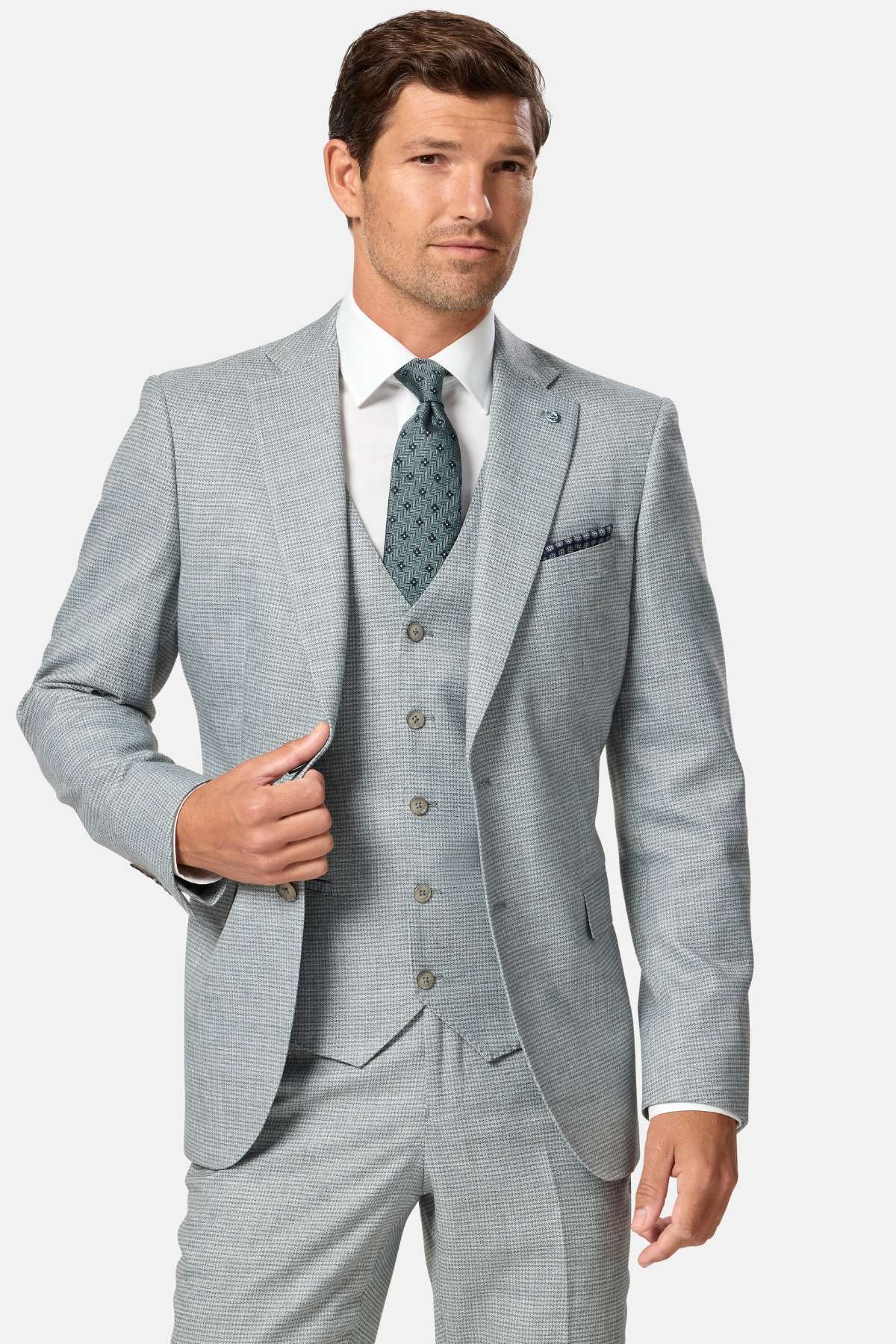 Man wearing a sage green checkered suit with a white shirt and patterned tie on a light gray background