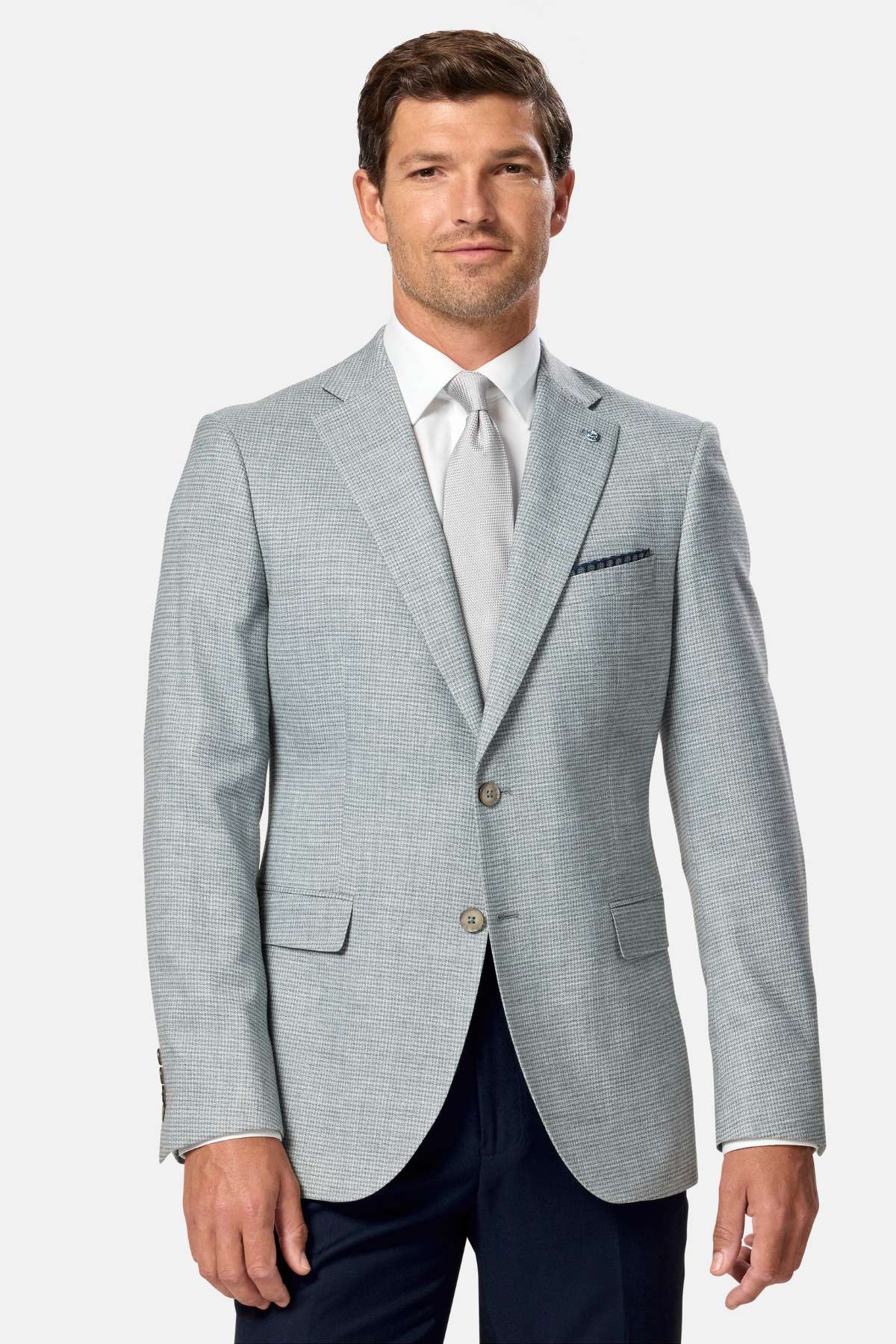 Man wearing a sage green checkered blazer over a white shirt with a tie on a white background
